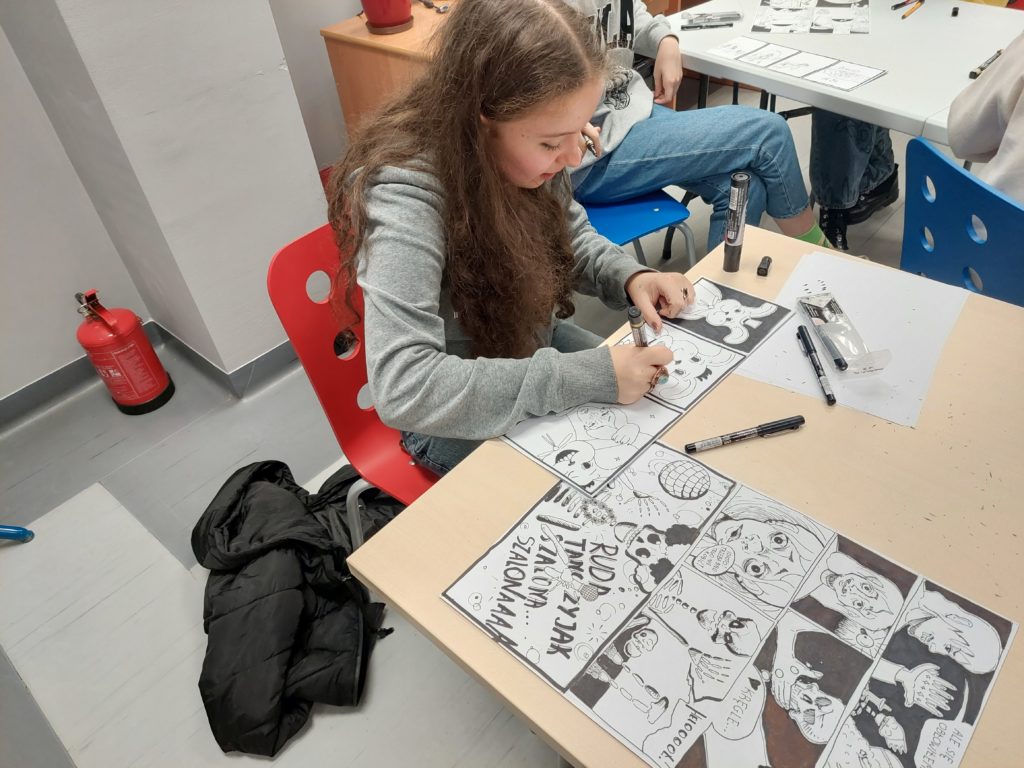 Dziewczyna przy stole w trakcie pracy nad komiksem