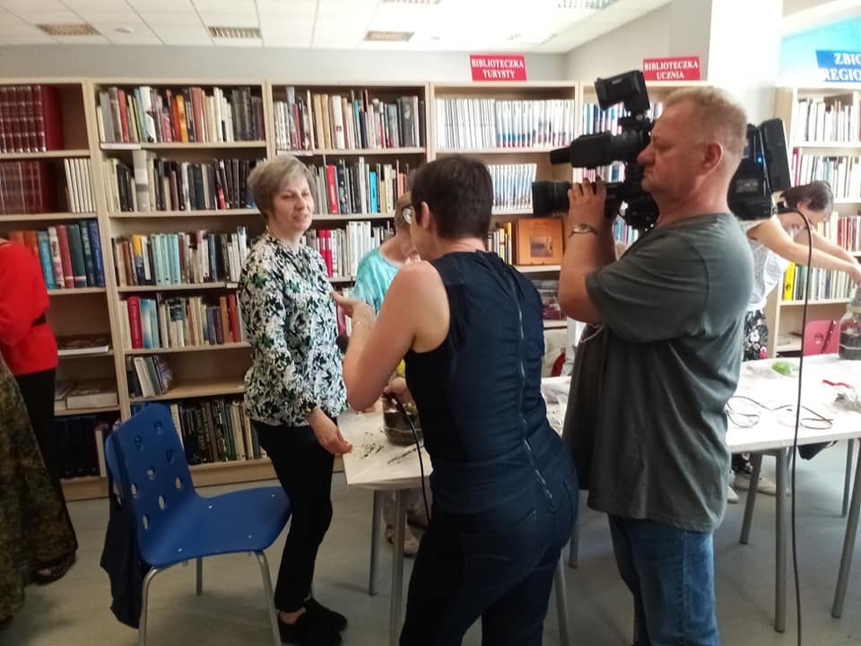 Czytelnia. Bibliotekarka udziela wywiadu redaktorce Telewizji Wrocław, obok stoi mężczyzna z kamerą.