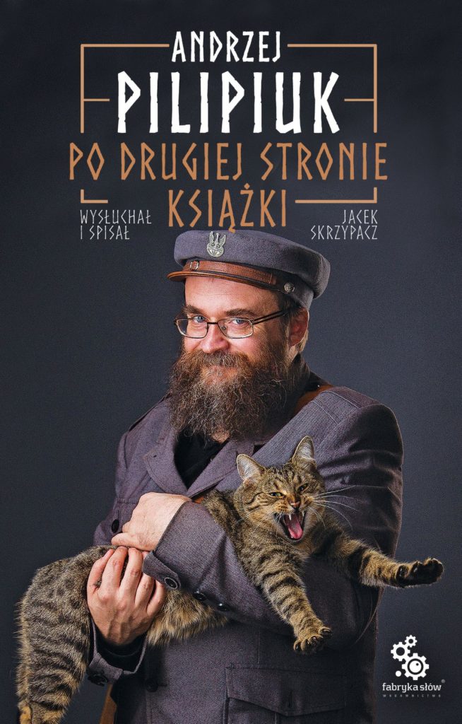 Na okładce mężczyzna w historycznym stroju trzyma kota. Tym mężczyzną jest Andrzej Pilipiuk.