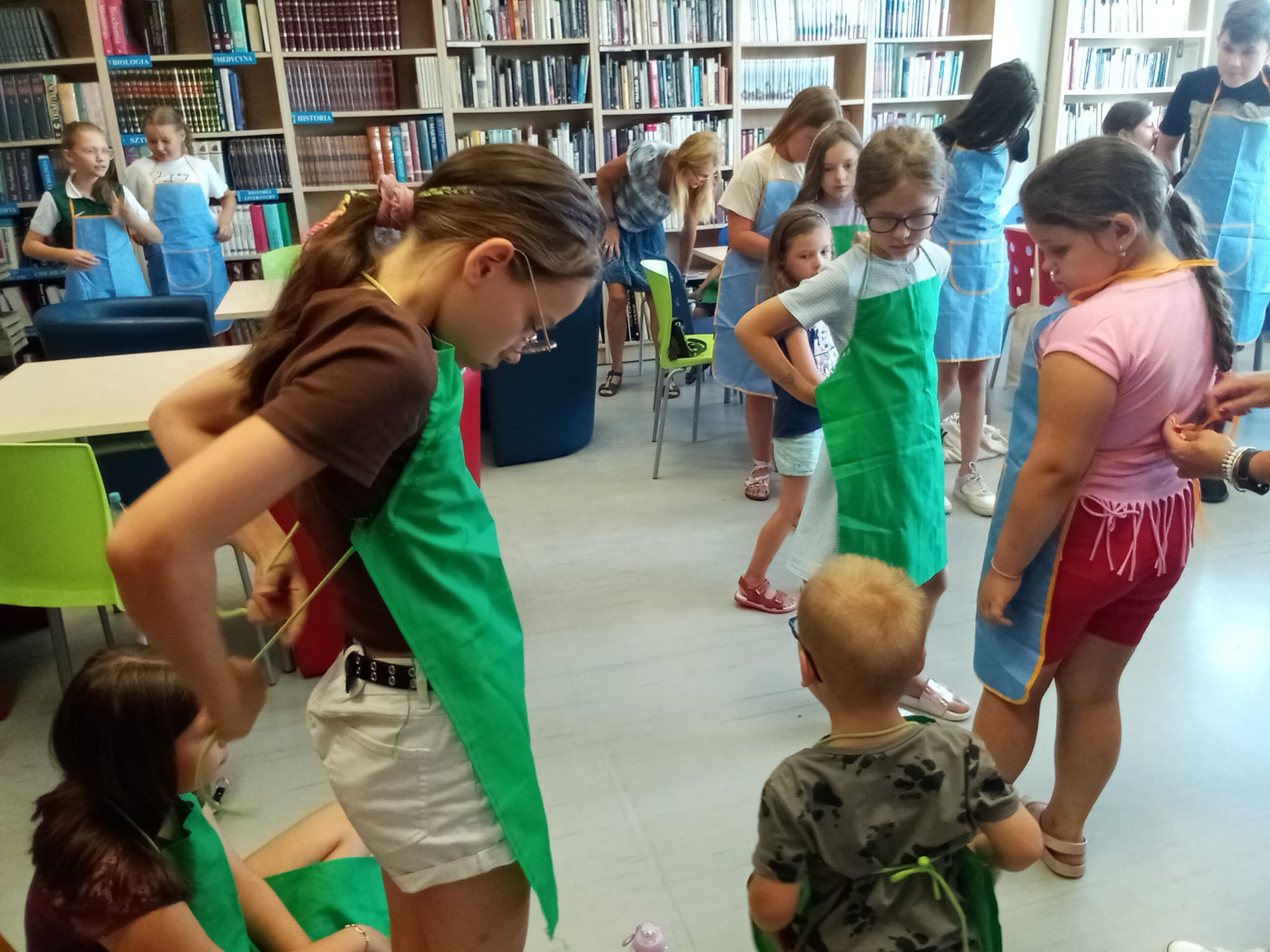 Biblioteka , czytelnia dla dorosłych. dzieci ubierają się w fartuszki ochronne.