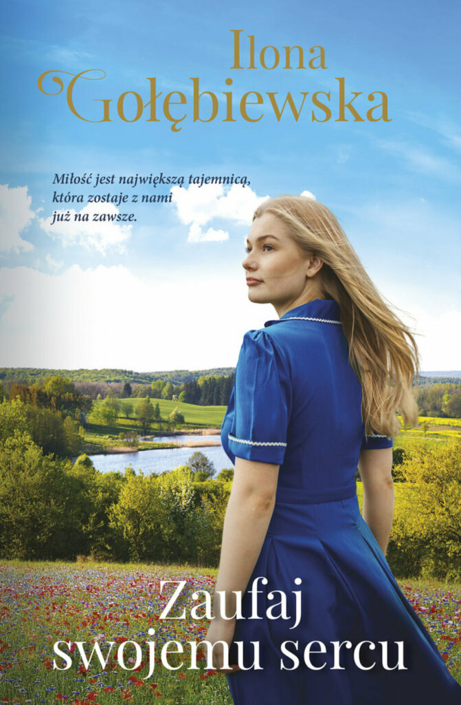 Na okładce kobieta w niebieskiej sukience o blond włosach na tle letniego krajobrazu łąki, jeziora, drzew