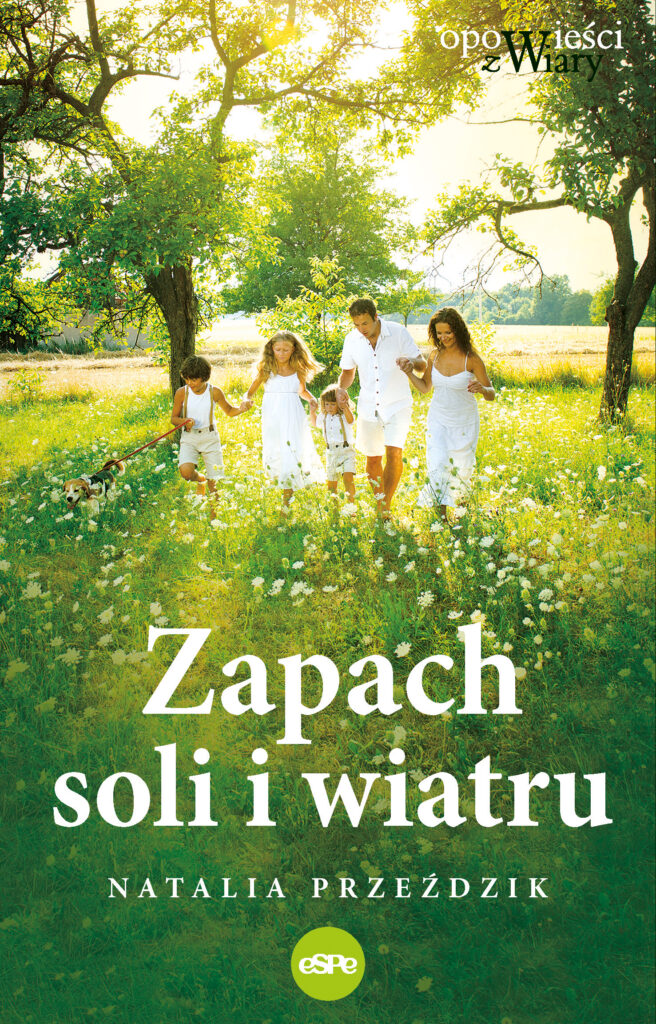 Ubrana na biało pięcioosobowa rodzina idąca przez zieloną polanę trzymając się za ręce. W tle zieleń, promienie słońca